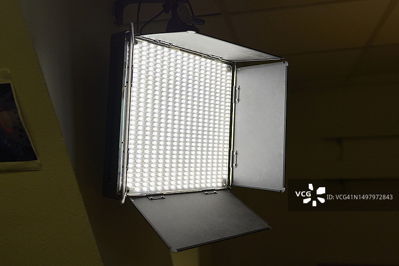 专业的LED面板灯打开并放置在墙上，同时照亮黑暗的房间图片素材