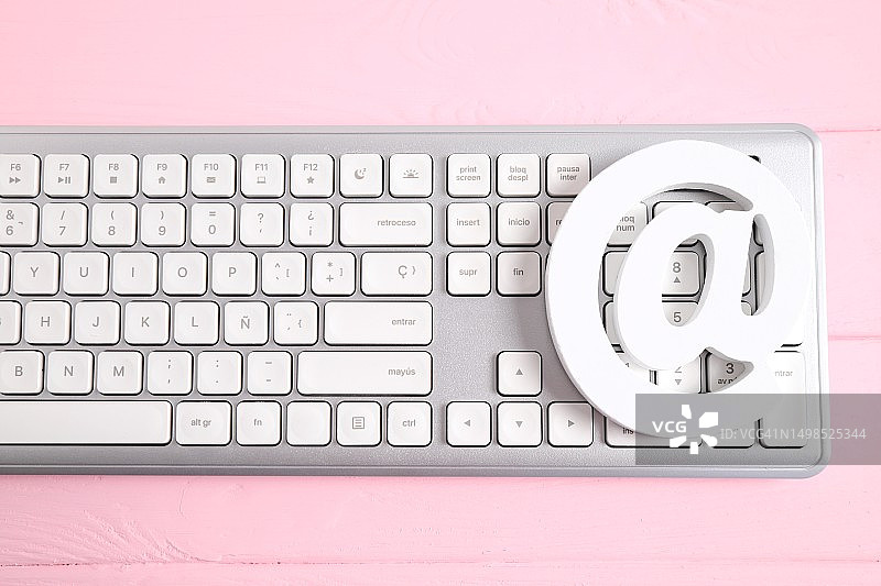 上图是西班牙粉红色背景上的电脑键盘和鼠标图片素材