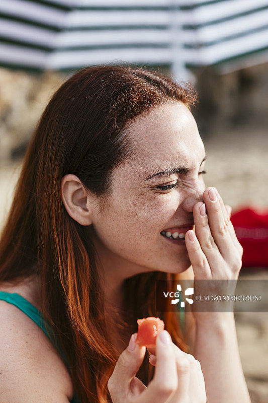 幸福的女人闭着眼睛在沙滩上抚摸鼻子图片素材
