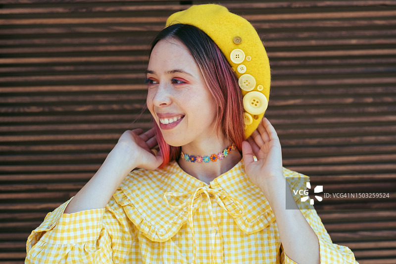 有魅力的年轻女子穿着一件黄色复古风格的有领衬衫，戴着一顶时髦的黄色贝雷帽。都市潮人时尚达人图片素材