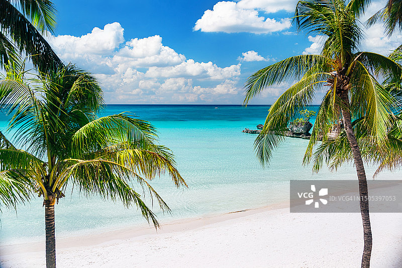 长滩岛空旷的白色沙滩上的棕榈树和威利岩群。图片素材