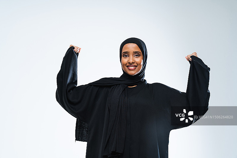 阿拉伯联合酋长国，戴着头巾的年轻女子站在白色背景下微笑着做手势图片素材