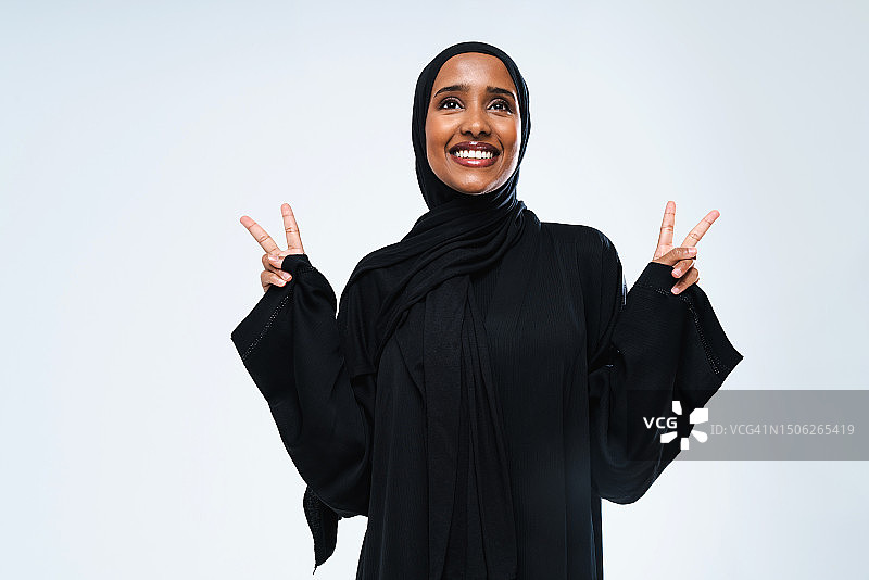 阿拉伯联合酋长国，站在白色背景下微笑的年轻女子在做手势图片素材