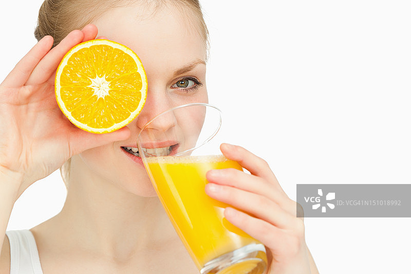 一个女人喝酒时把橘子放在眼睛上图片素材