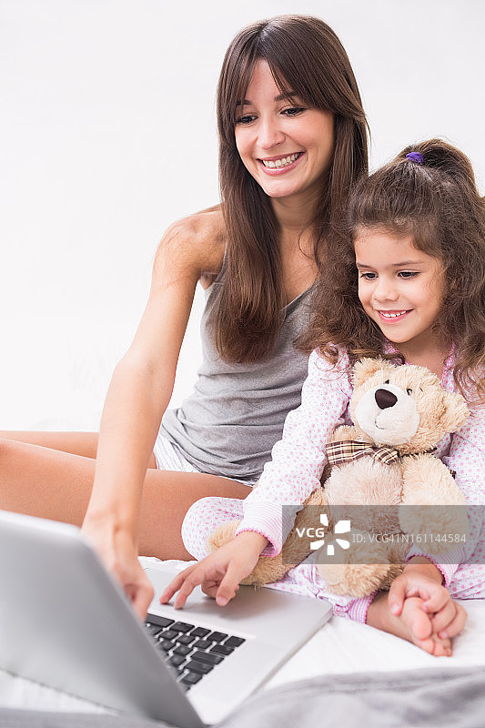妈妈和女儿用手提电脑和泰迪熊图片素材