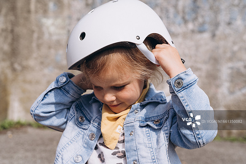 时尚可爱的学龄前女孩把一个保护头盔戴在头上图片素材