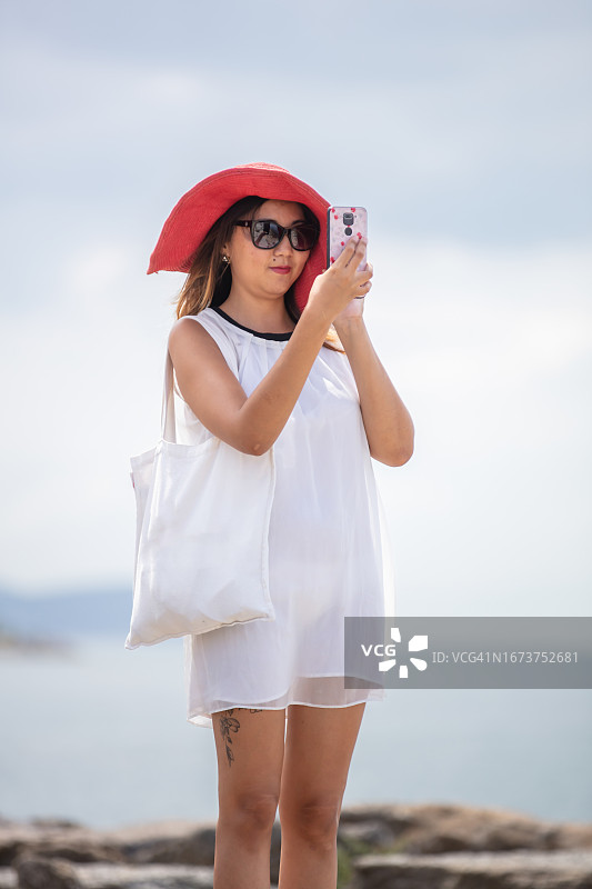 年轻的亚洲女游客正在用她的手机拍照。图片素材
