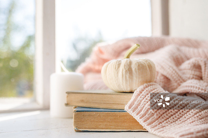 窗台上舒适的秋天毛衣。静物画，书和小装饰南瓜。图片素材