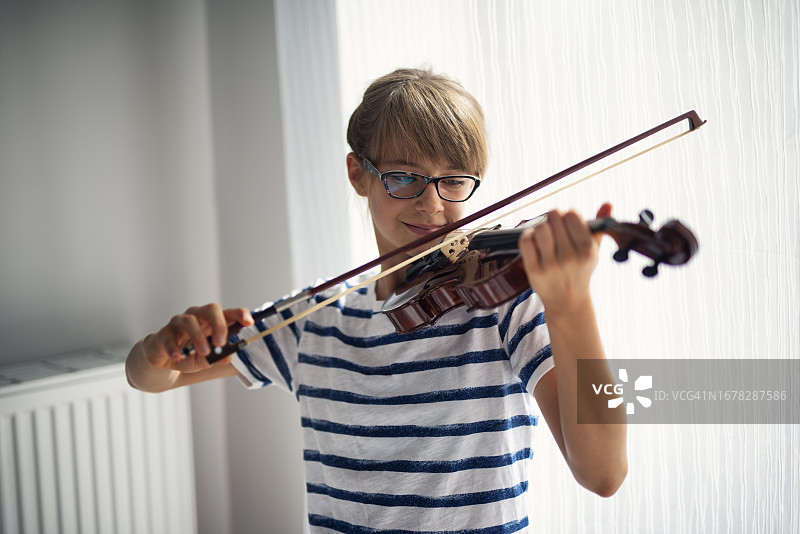 快乐的小女孩在家练习小提琴图片素材