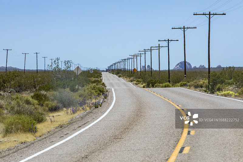 美国，加利福尼亚，巴斯托，莫哈韦国家保护区，沙漠中空旷的高速公路和电力塔图片素材