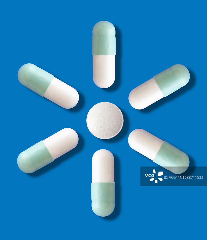 药物以药丸和胶囊的形式出现在蓝色背景和一个小阴影上。图片素材