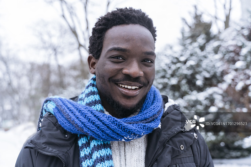 冬天戴着蓝围巾微笑的年轻人图片素材