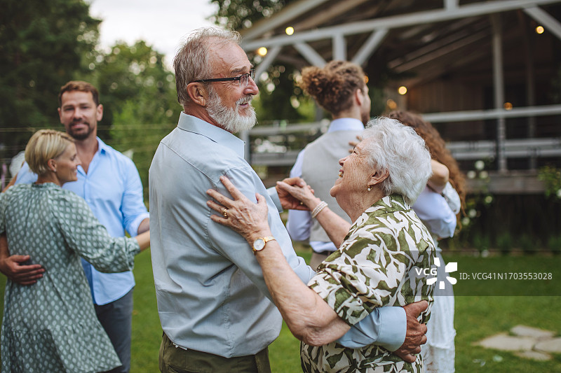 一对老年夫妇在户外花园派对上跳舞。夏日家庭花园庆典。图片素材