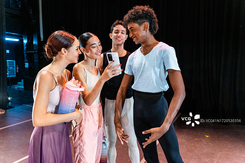 年轻的芭蕾舞演员在舞台剧院使用手机图片素材