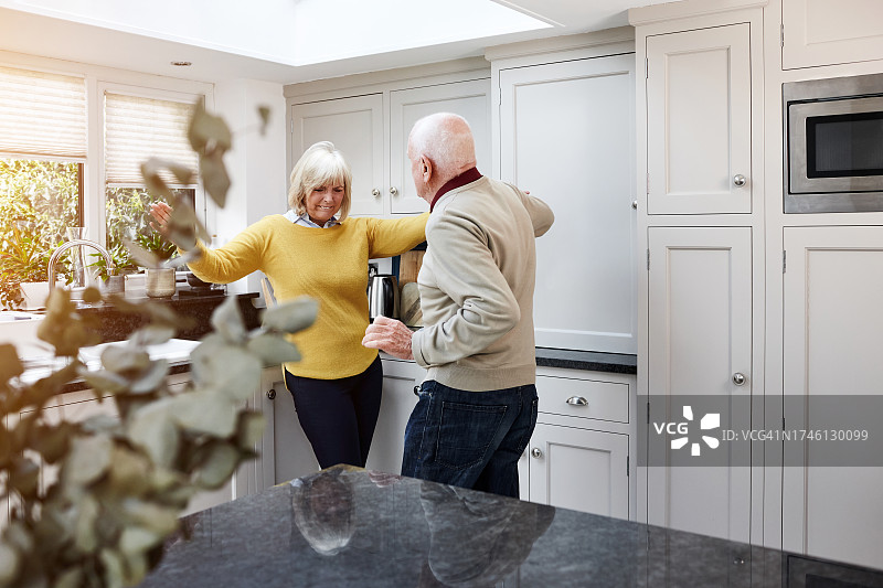跳舞，快乐和老年夫妇在厨房房间里与音乐，爱和纽带在他们的家。退休，庆祝和老人在一个房子里的收音机，播客或乐趣与关心，信任或支持图片素材
