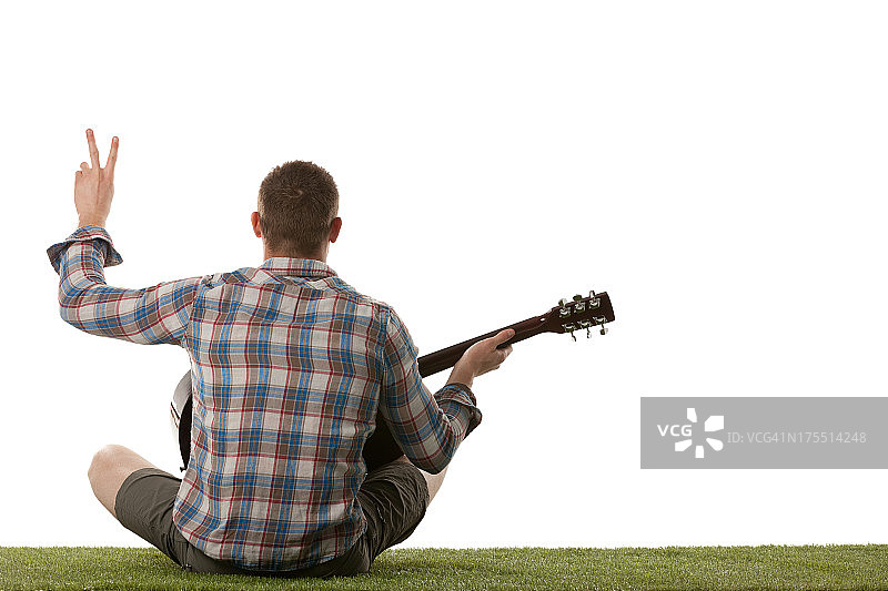 一个男人弹吉他并显示“V”的后视图图片素材