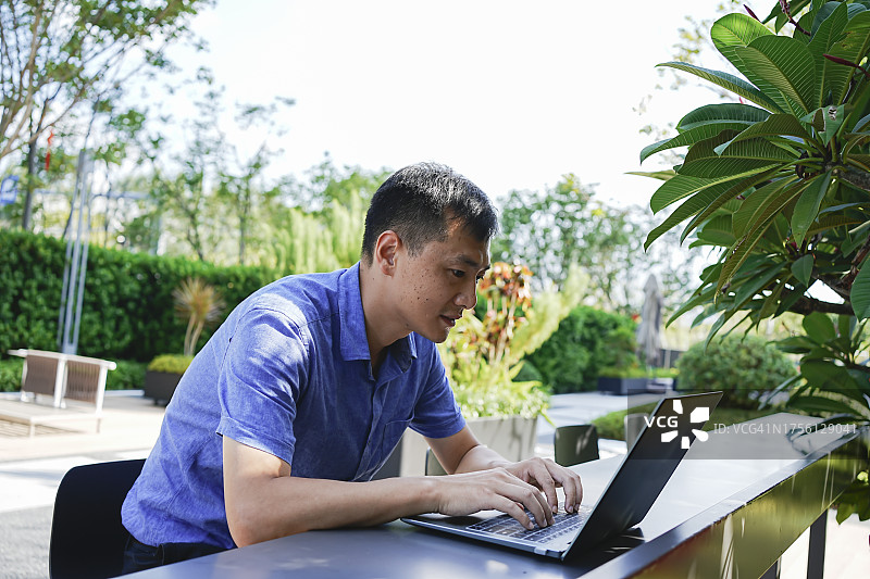 一名男子坐在郊外使用笔记本电脑图片素材