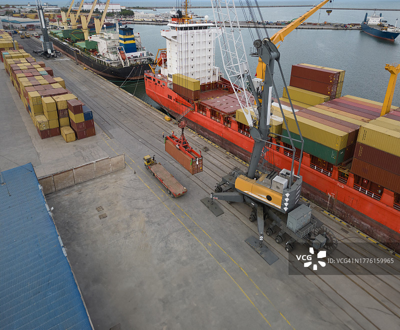 集装箱在港口用起重机运输的鸟瞰图。集装箱船装载。图片素材