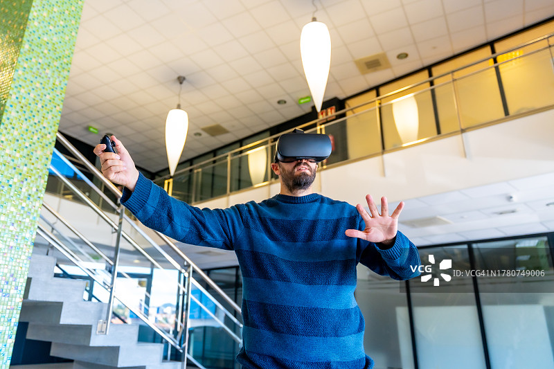 员工在办公室戴上虚拟现实眼镜，在工作中体验网络空间。一个办公室职员触摸数字世界中的物体，一个商人戴着3d眼镜与虚拟现实互动图片素材