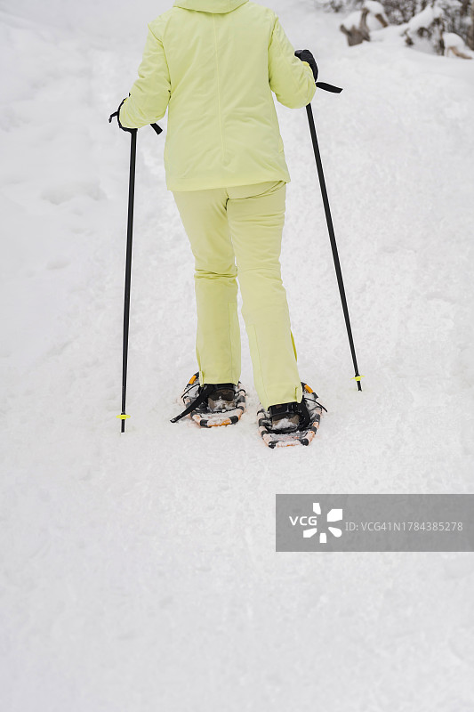 无法辨认的女徒步者穿着雪鞋在山上的后视图图片素材