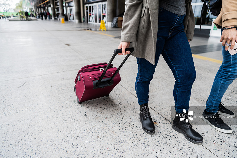 低段的一位女士提着行李箱走在机场外图片素材