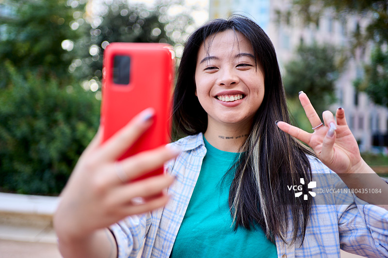 开心的中国女孩用智能手机自拍。图片素材