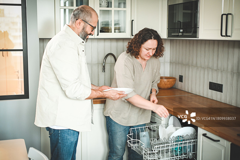 丈夫和妻子把盘子放进洗碗机图片素材