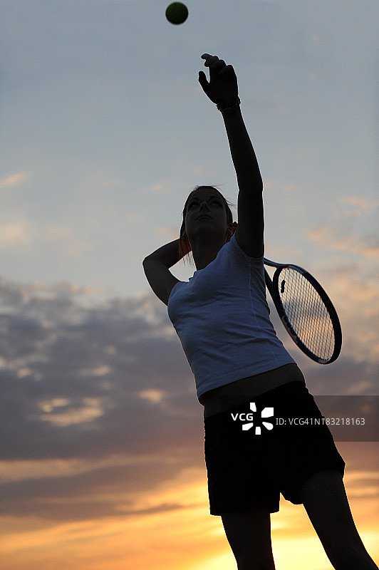 女子网球运动员在日落时发球图片素材