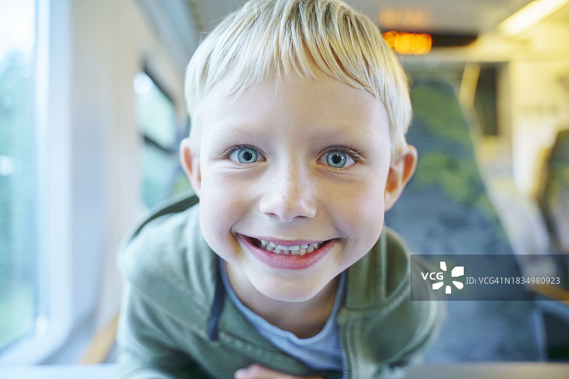 快乐的金发男孩在火车上旅行图片素材