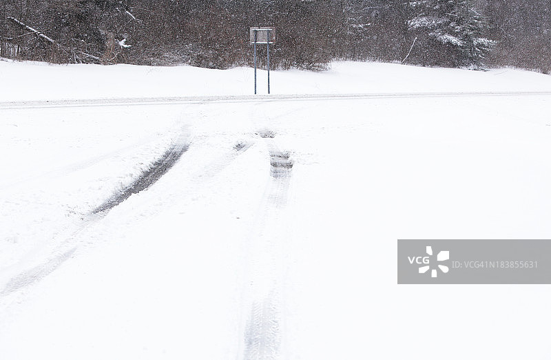 冬季暴风雪期间乡村休息站入口的轮胎痕迹图片素材