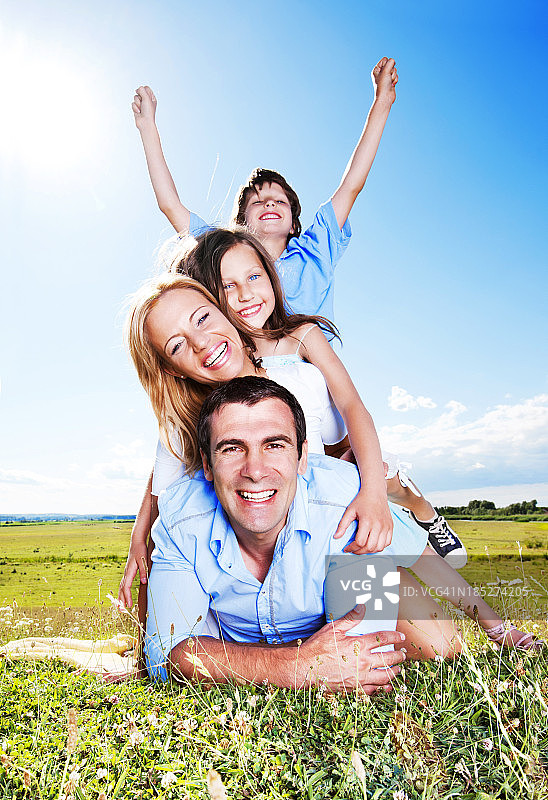 幸福的一家人坐在户外，背靠蓝天图片素材