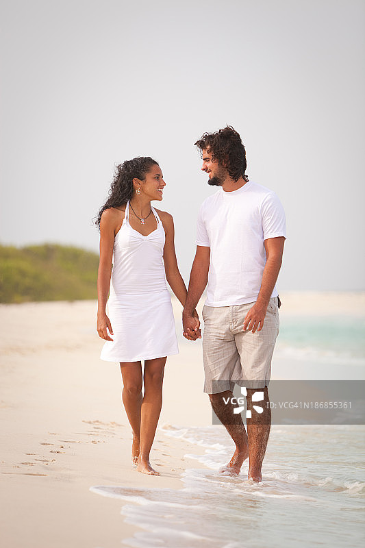 一对幸福的订婚情侣在热带海滩散步图片素材