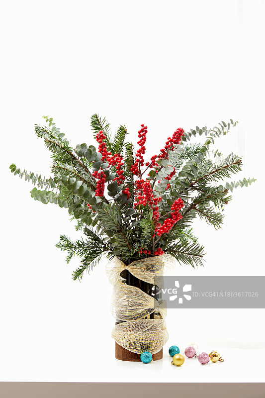 冷杉树枝和冬青浆果的特写，花瓶里放着圣诞小装饰品图片素材
