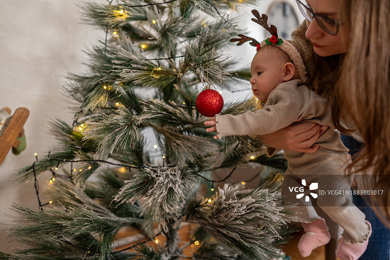 早上，妈妈和她的小女儿在圣诞树旁图片素材