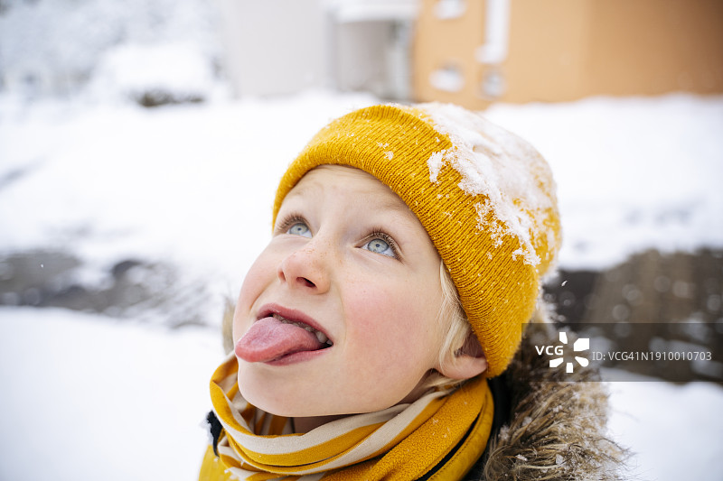 男孩在冬天用舌头接雪图片素材