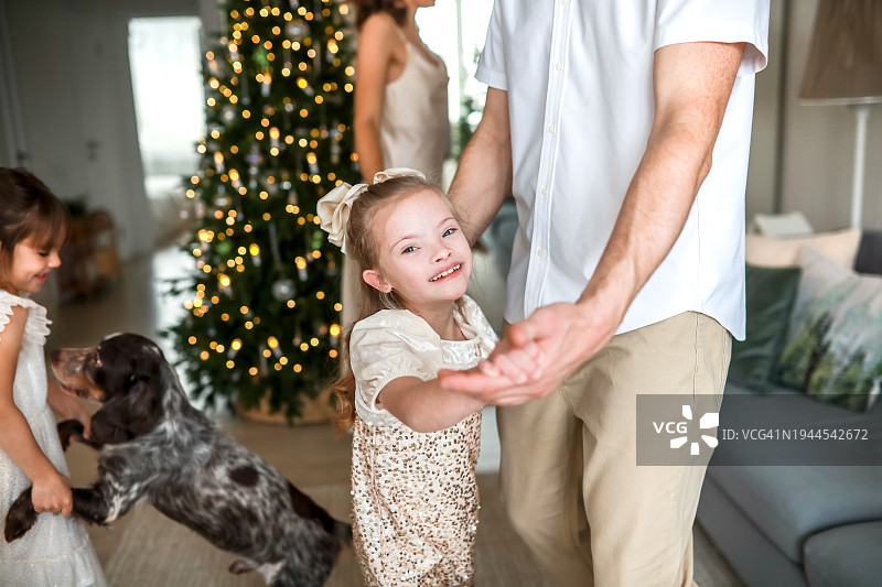 圣诞快乐:特别时刻的父女舞。患有唐氏综合症的女孩和她的爸爸跳舞。图片素材