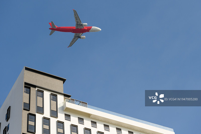 商用飞机飞过摩天大楼的低角度视角图片素材
