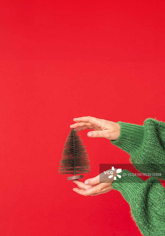 裁剪的手拿着绿色背景的圣诞装饰图片素材