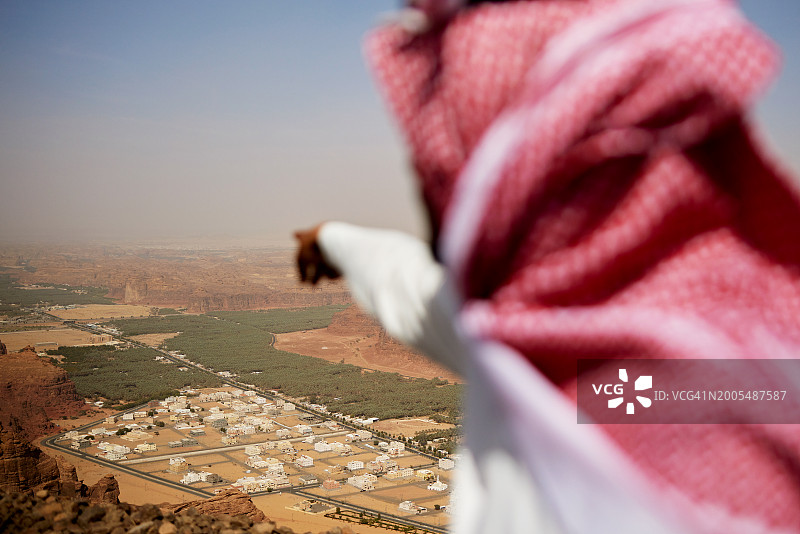 导游从哈拉特观景台指向Al-Ula山谷图片素材