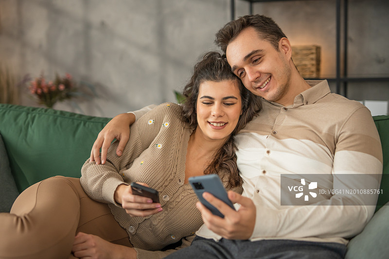 一对夫妇在家里放松，用手机玩科技产品图片素材