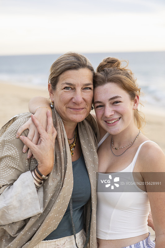 海滩上微笑的母亲和十几岁的女儿的肖像图片素材