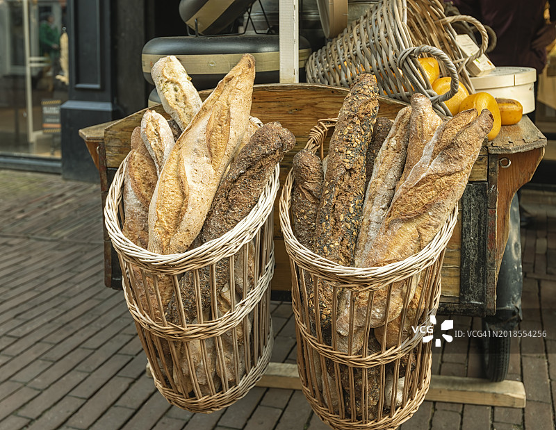 新鲜出炉的法棍面包放在外面的柳条篮子里出售图片素材