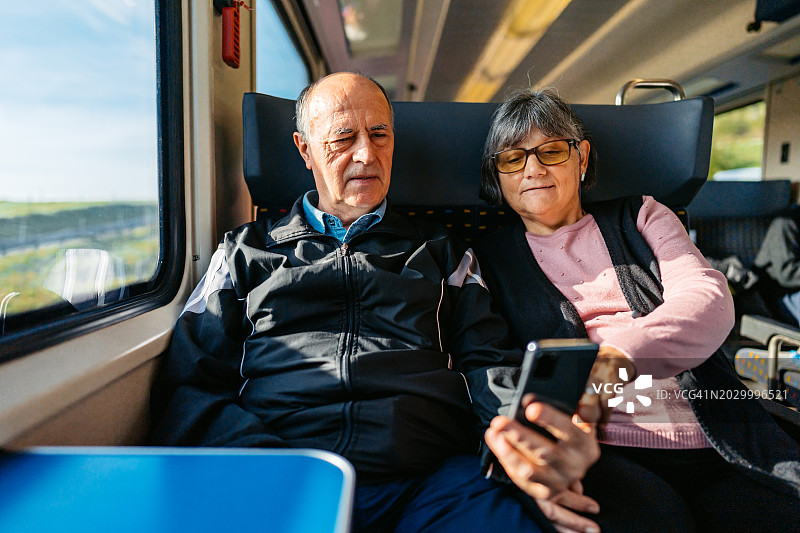 瑞士一对老年夫妇在火车上用智能手机查找路线图片素材