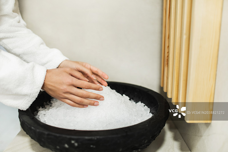 用冷雪擦拭身体，使身体硬化。蒸桑拿时，女性用手捧着碗里的雪图片素材