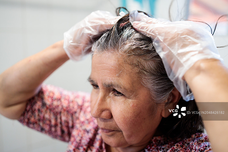 自给造型:资深拉丁女性掌柜特写，在浴室独立染发。图片素材