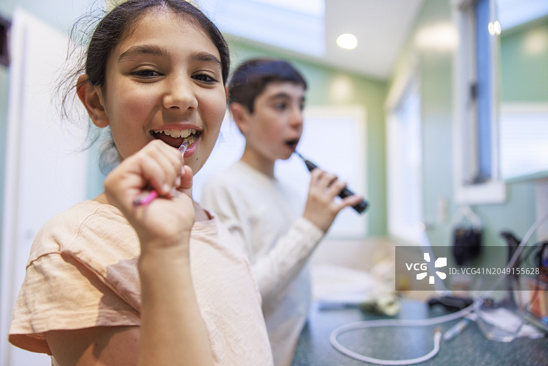 快乐的孩子们在浴室里刷牙时对着镜头摆姿势图片素材