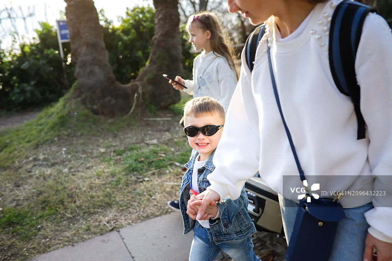 一起探索:中年妈妈和儿子带着双肩包和旅行箱漫步，开始他们的假期。图片素材