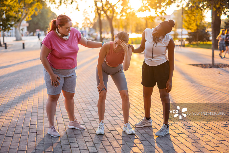两位女性朋友在公园慢跑后支持她们的朋友图片素材