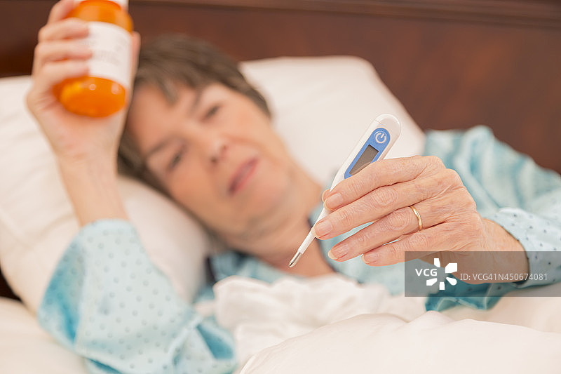 医疗保健:患流感卧床不起的妇女。温度计。图片素材