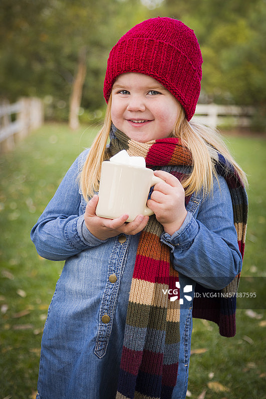 可爱的年轻女孩拿着可可杯和棉花糖在外面图片素材
